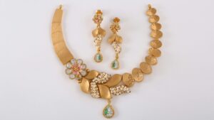 Elegance redefined – a stunning gold jewelry set adorned with pearls, intricate floral motifs, and sparkling green gemstones, perfect for a timeless and graceful look